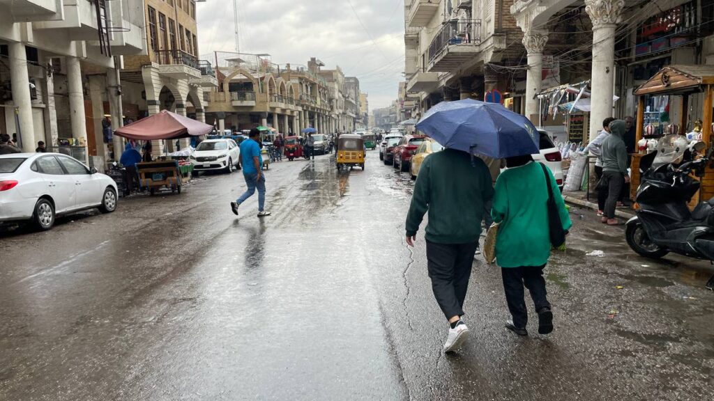 صور من حياة الشارع في بغداد: اليوم الأول لارتداء "القمصلة" وحمل مظلات المطر